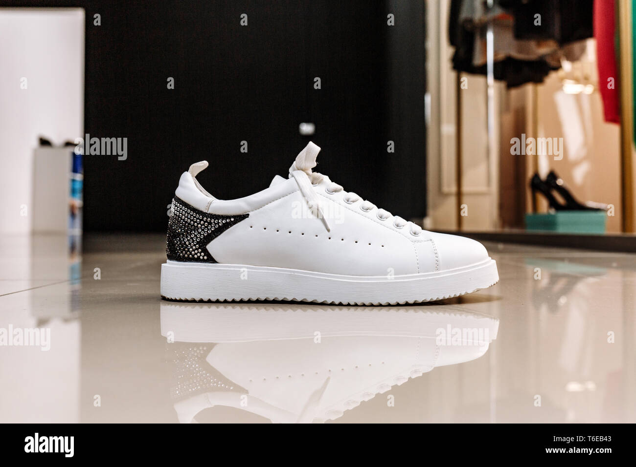 Bianco elegante sneaker con un ornamento stella fatta di pietre strass sullo sfondo sul pavimento chiaro Foto Stock