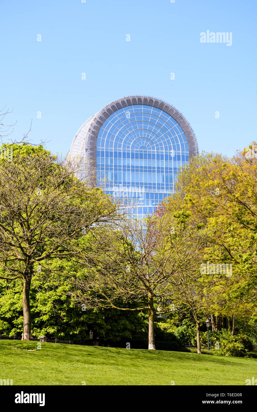 Il tetto in vetro dell'edificio Paul-Henri Spaak, la sede del Parlamento europeo a Bruxelles, sporgenti al di sopra gli alberi del Parco Leopold. Foto Stock
