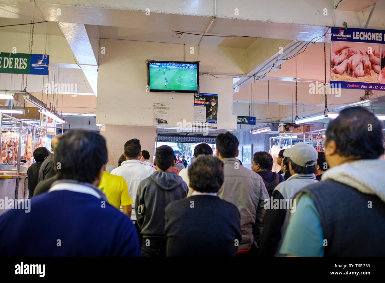 La gente guarda il calcio su un monitor televisivo all'interno del Mercato Centrale o Mercado Central a Lima in Perù Foto Stock