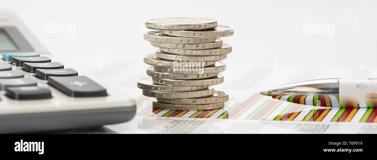 Impilate le monete in euro e la calcolatrice posa su attività finanziarie grafico del mercato azionario Foto Stock
