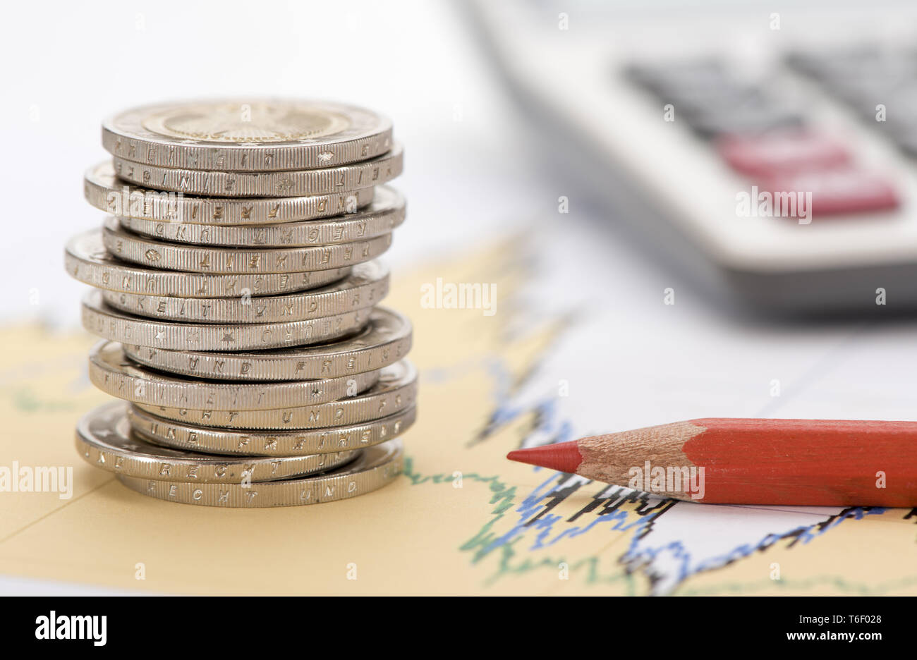 Impilate le monete in euro e la calcolatrice posa su attività finanziarie grafico del mercato azionario Foto Stock