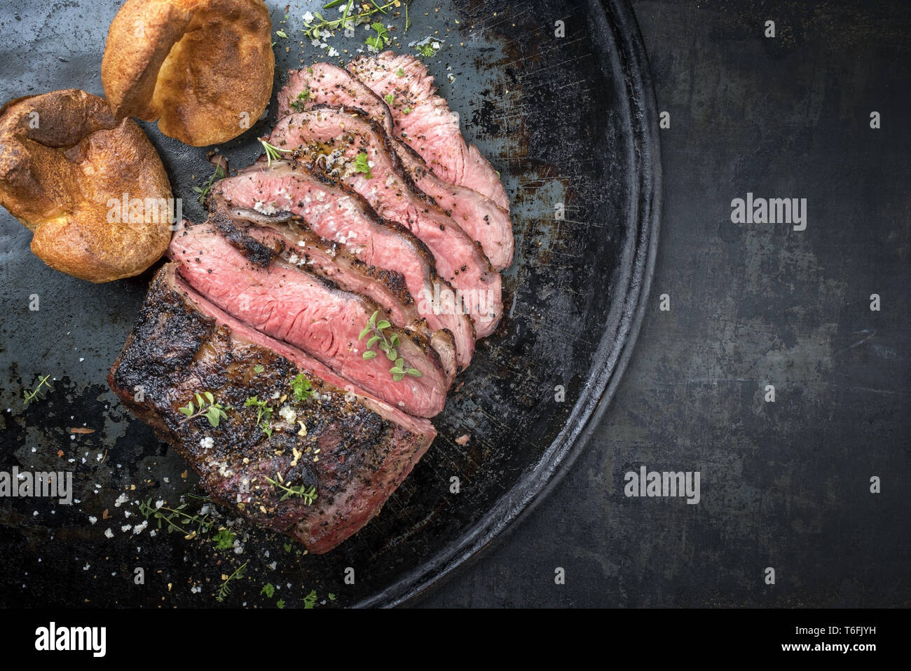 Barbecue wagyu carne arrosto affettata con Yorkshire pudding come vista dall'alto su un vassoio con spazio copia a destra Foto Stock