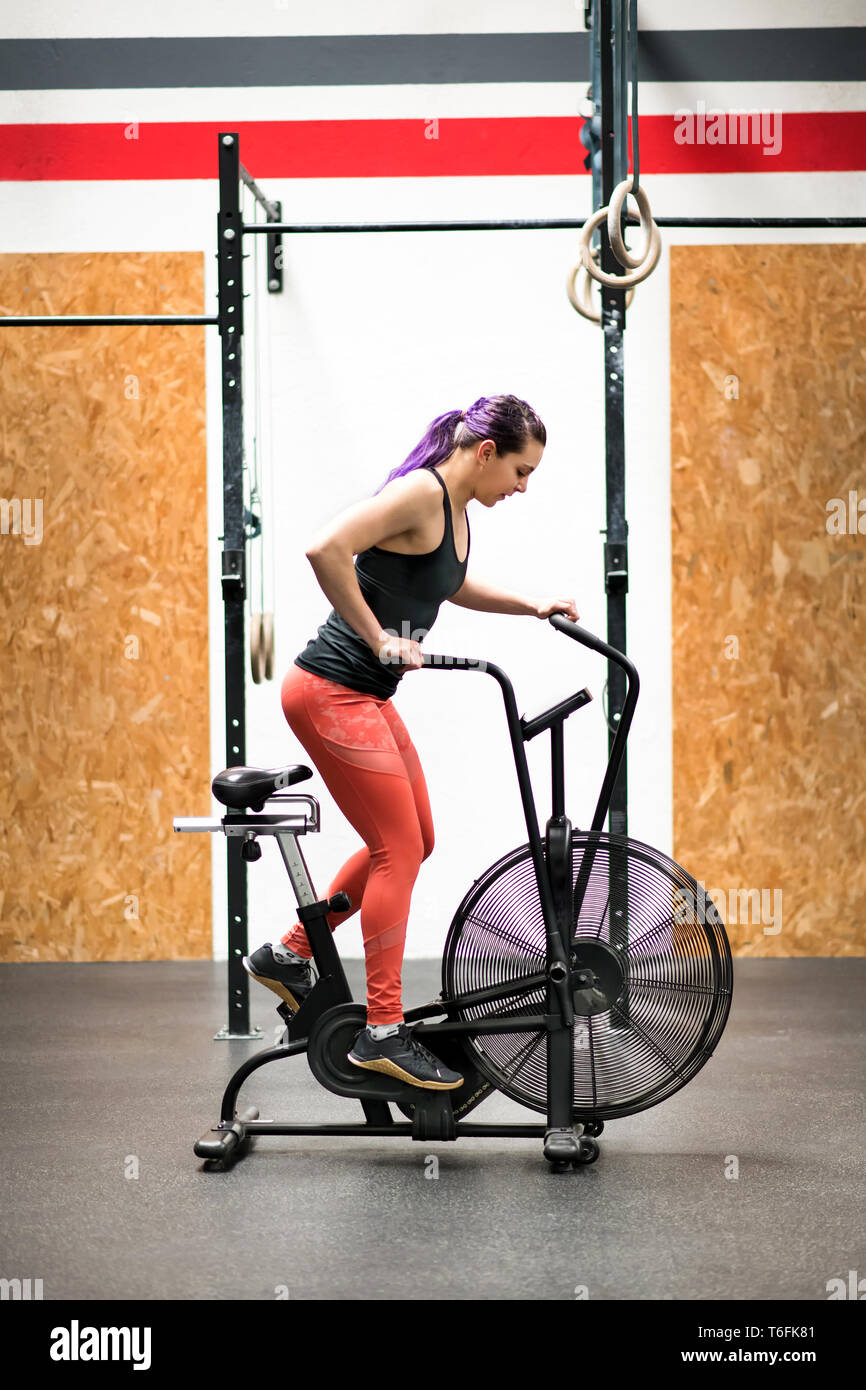 Giovane atleta donna che lavora fuori in posizione eretta su una cyclette  in una palestra in