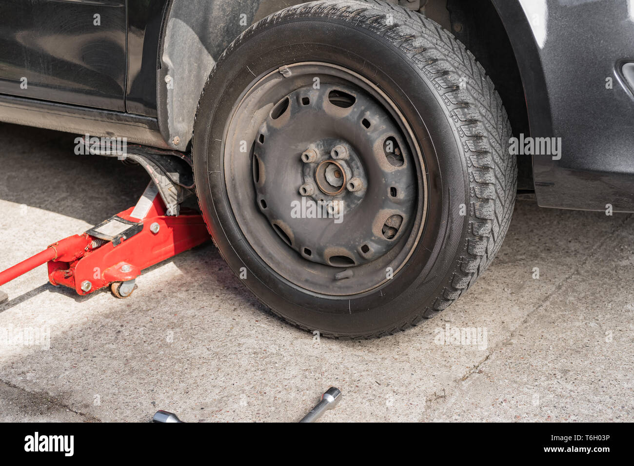 Auto sollevato su un viale di accesso. Pneumatico stagionale cambiare o servizio concetto astratto. Foto Stock