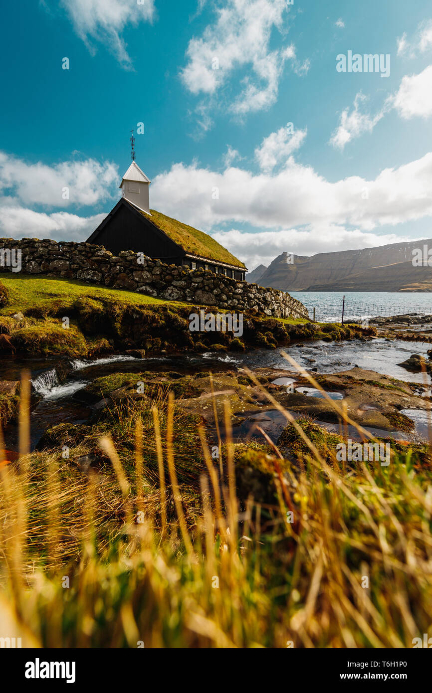 Il piccolo e pittoresco di legno nero chiesa di Funningur (Funnings Kirkja) durante una soleggiata giornata di primavera con drammatica nuvole (Isole Faerøer, Danimarca) Foto Stock
