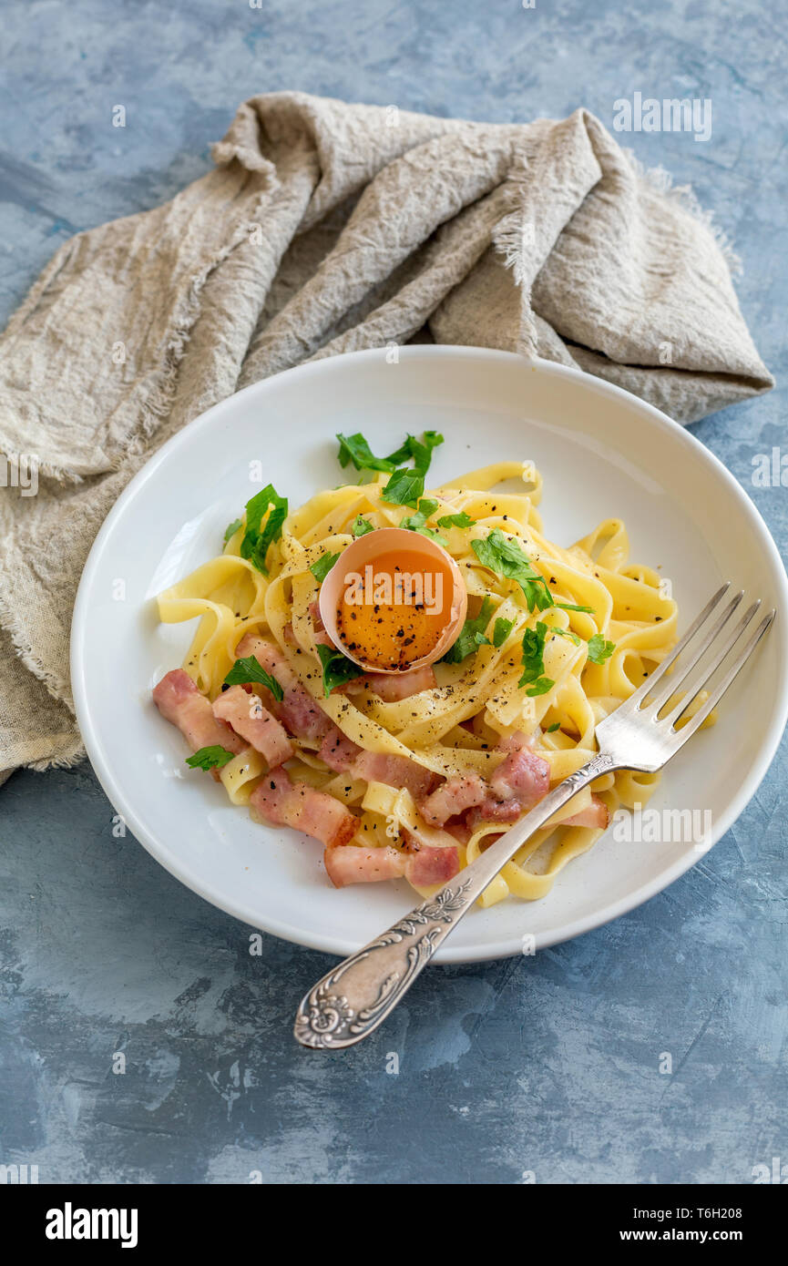 La pasta alla carbonara con tuorlo d'uovo in una piastra bianca. Foto Stock