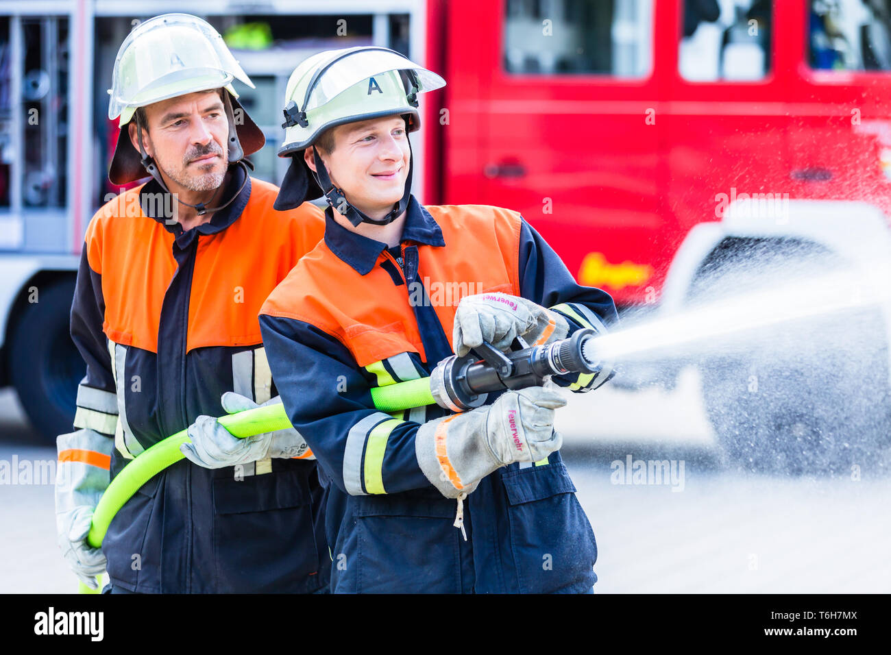 Gli uomini dei vigili del fuoco di spegnere un incendio Foto Stock