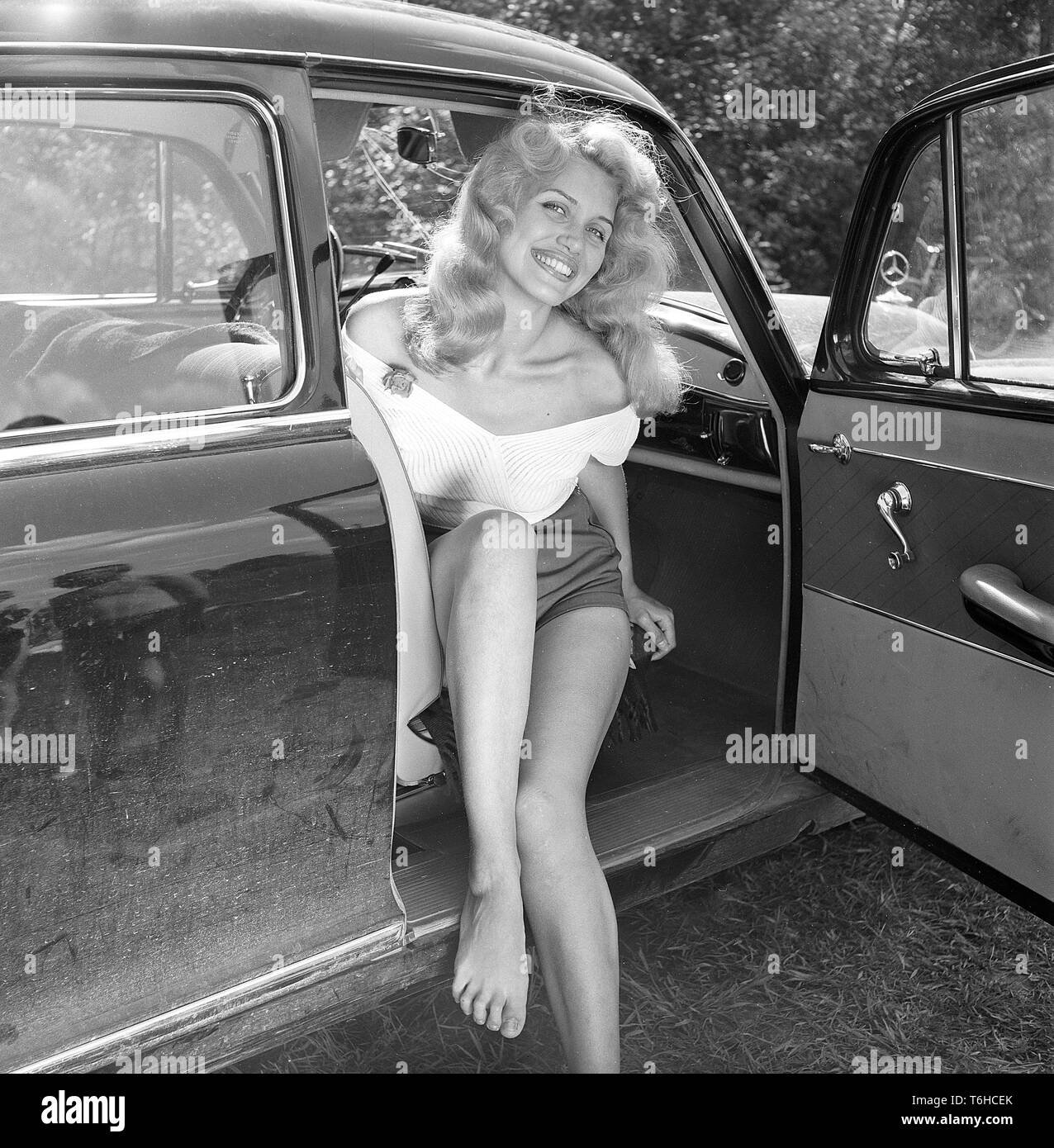 Anni Cinquanta l'estate. Una giovane donna bionda con un grande sorriso sul suo volto, vestito in pantaloncini corti e un ponticello è seduto in un'auto. Foto Kristoffersson ref BX105-9. La Svezia 1956 Foto Stock