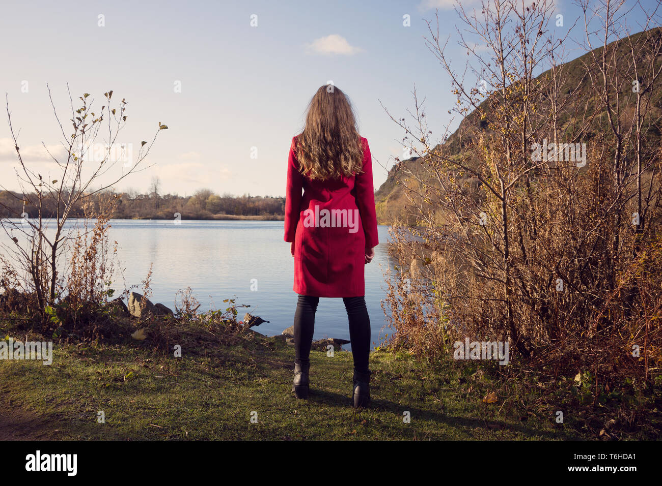 Giovane donna guarda oltre Duddingston Loch in Edinburgh Foto Stock