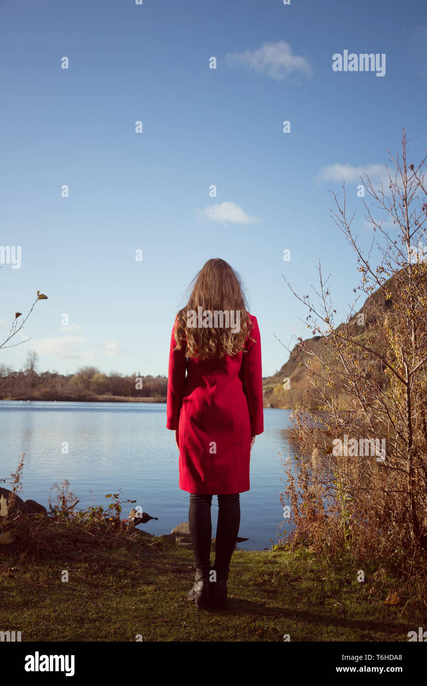 Giovane donna guarda oltre Duddingston Loch in Edinburgh Foto Stock