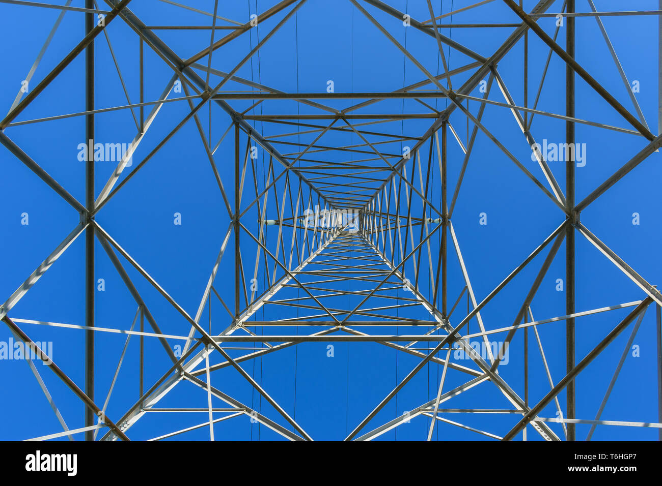 Di energia elettrica ad alta tensione vista polo dal di sotto il cielo blu Foto Stock