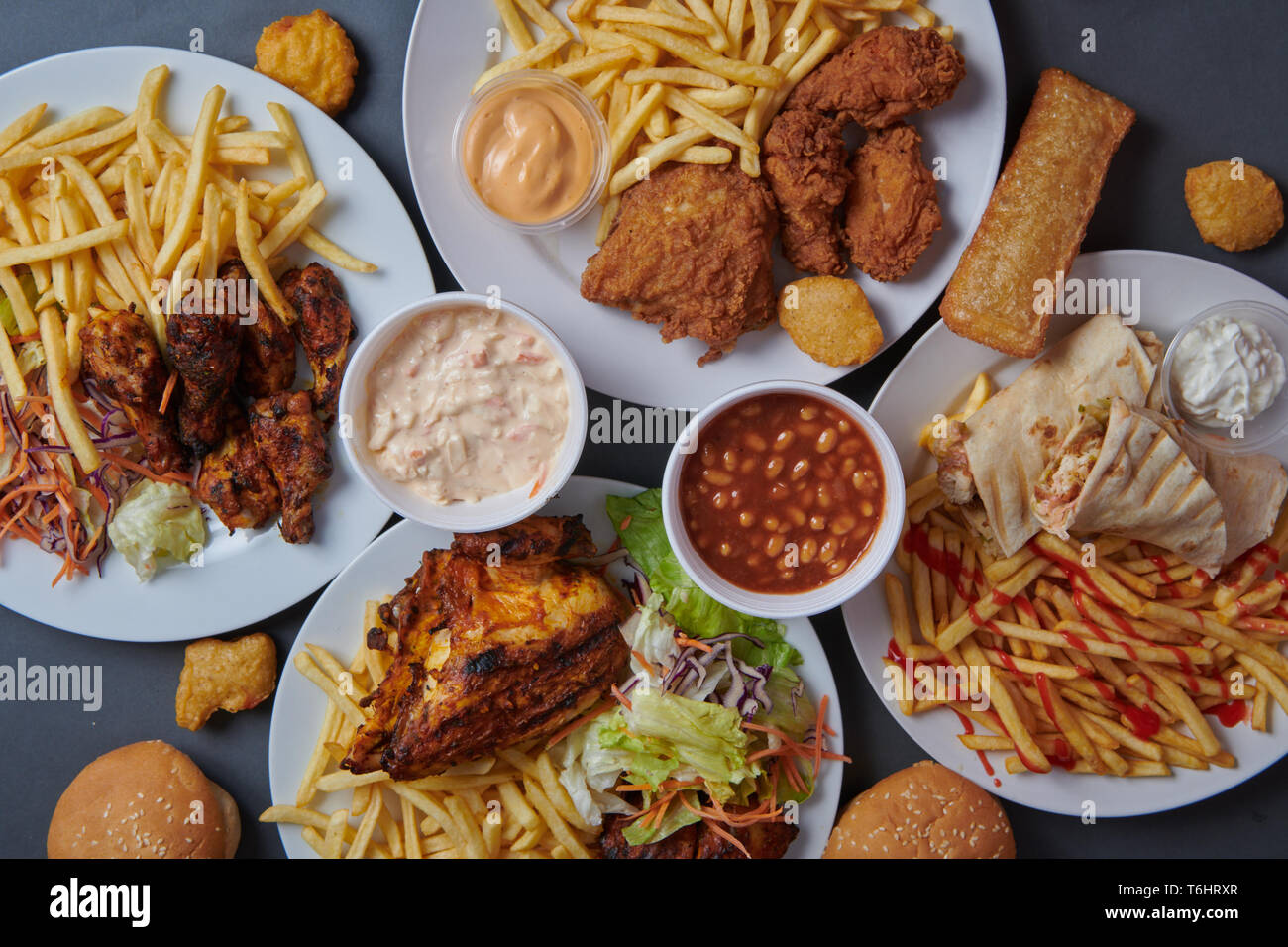 Una selezione di fritti e pollo grigliato su sfondo grigio Foto Stock