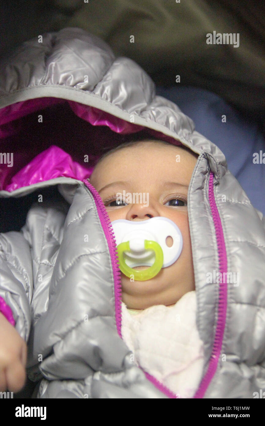 Ritratto di un piccolo grazioso Baby girl in giacca bambino succhiare il ciuccio. Foto Stock