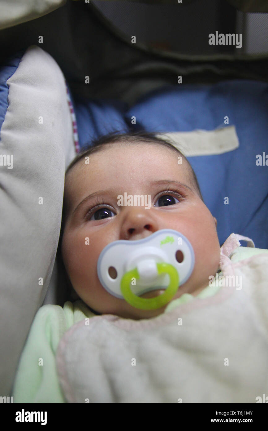 Ritratto di una incantevole piccola bambina nella baby pram succhiare il ciuccio. Foto Stock