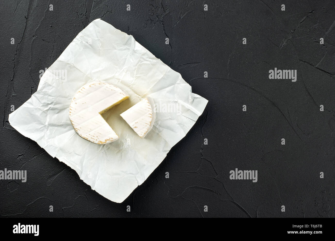 Formaggio Brie con una fetta di carta nella confezione aperta su sfondo scuro Foto Stock