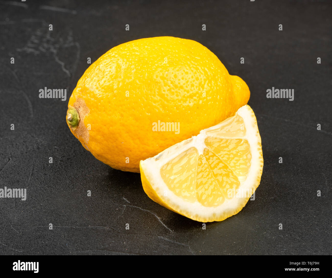 Limone con succosa fetta su sfondo scuro Foto Stock