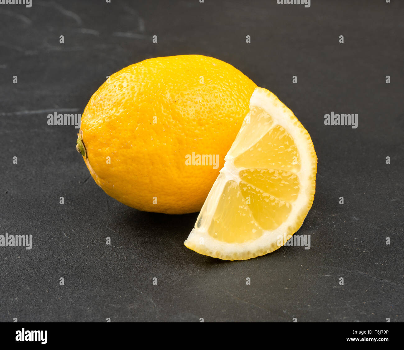 Limone con succosa fetta su sfondo scuro Foto Stock