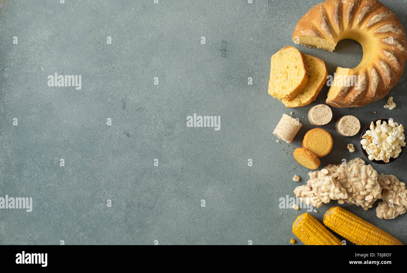 Festa Junina cibo tradizionale background,copia di spazio per il testo. Dolci deliziosi per brasiliano Festa Junina Party: Torta di farina di mais Bolo de Fuba, mais Biscotti,popcorn,peanut candy Pacoca, mais orecchio vista superiore Foto Stock