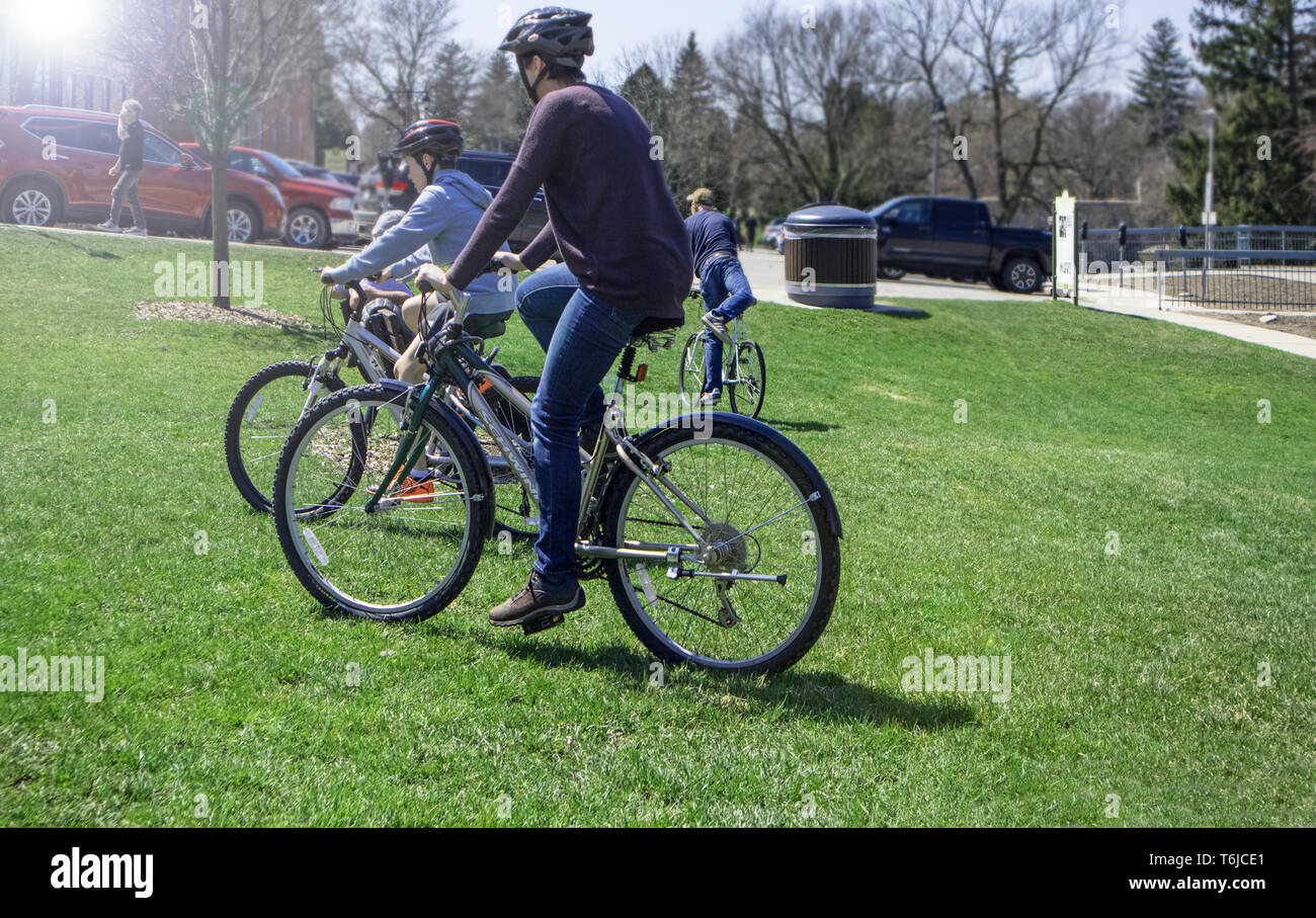 Sull'erba nel parco, off il sentiero, una famiglia ventures con le loro biciclette. Foto Stock