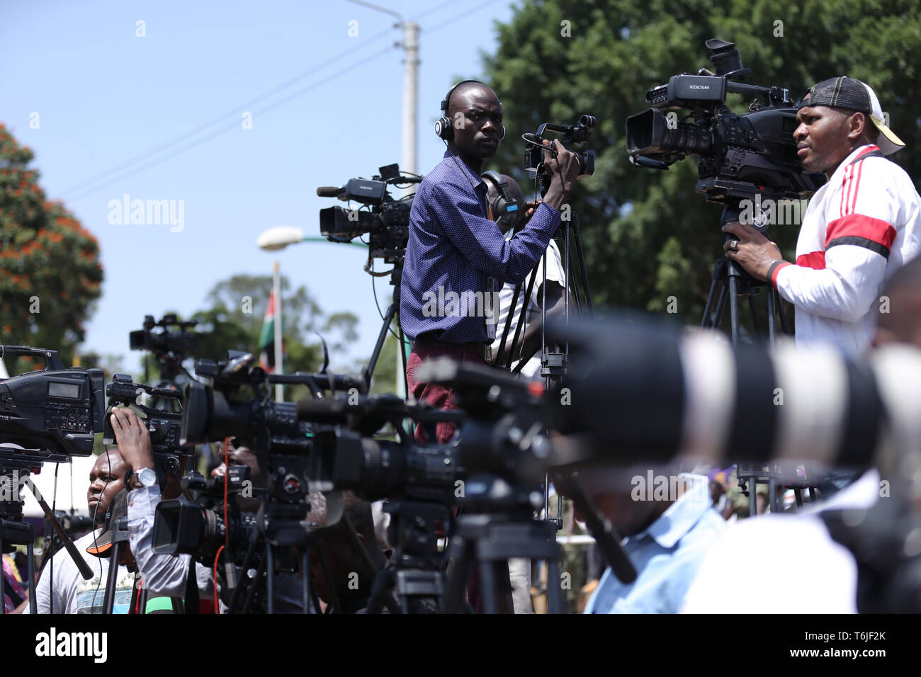 I membri dei media si vede la copertura durante i festeggiamenti. I keniani hanno celebrato la festa del lavoro a Uhuru Park di Nairobi dove alcuni giovani hanno protestato contro la corruzione dilagante e scarsa leadership in Kenya. La disoccupazione e la sottoccupazione è diffusa nel paese. Foto Stock