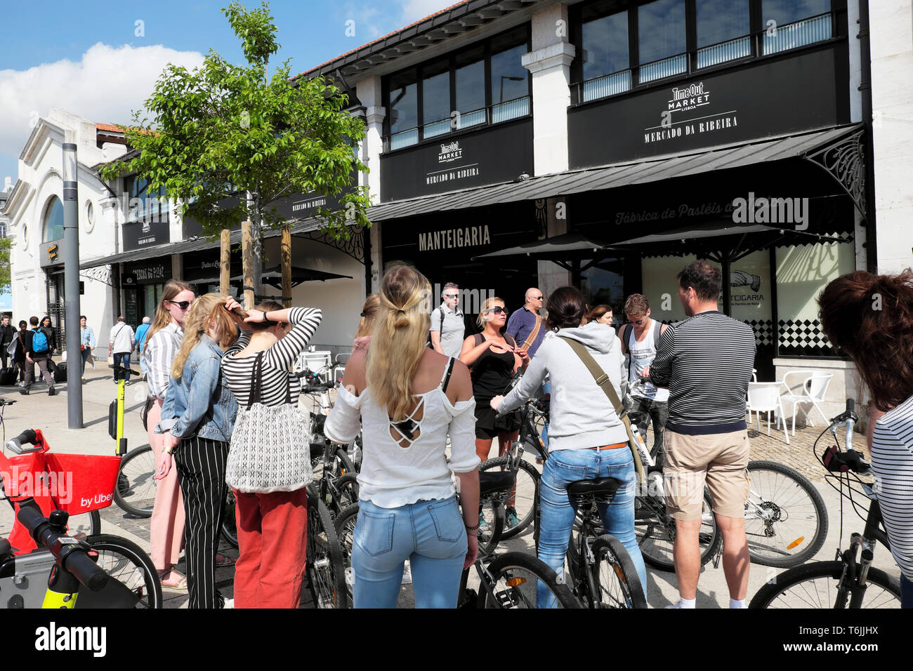 Giovani con biciclette a noleggio bici e tour guida al di fuori del tempo fuori mercato alimentare di edificio ingresso Ribeira Lisbona Lisboa Portogallo Europa KATHY DEWITT Foto Stock