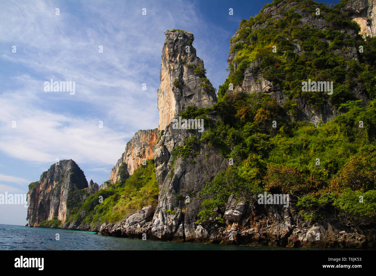 Gita in barca lungo la costa di Isola tropicale Ko Phi Phi lungo impressionanti formazioni rocciose sotto il cielo blu Foto Stock