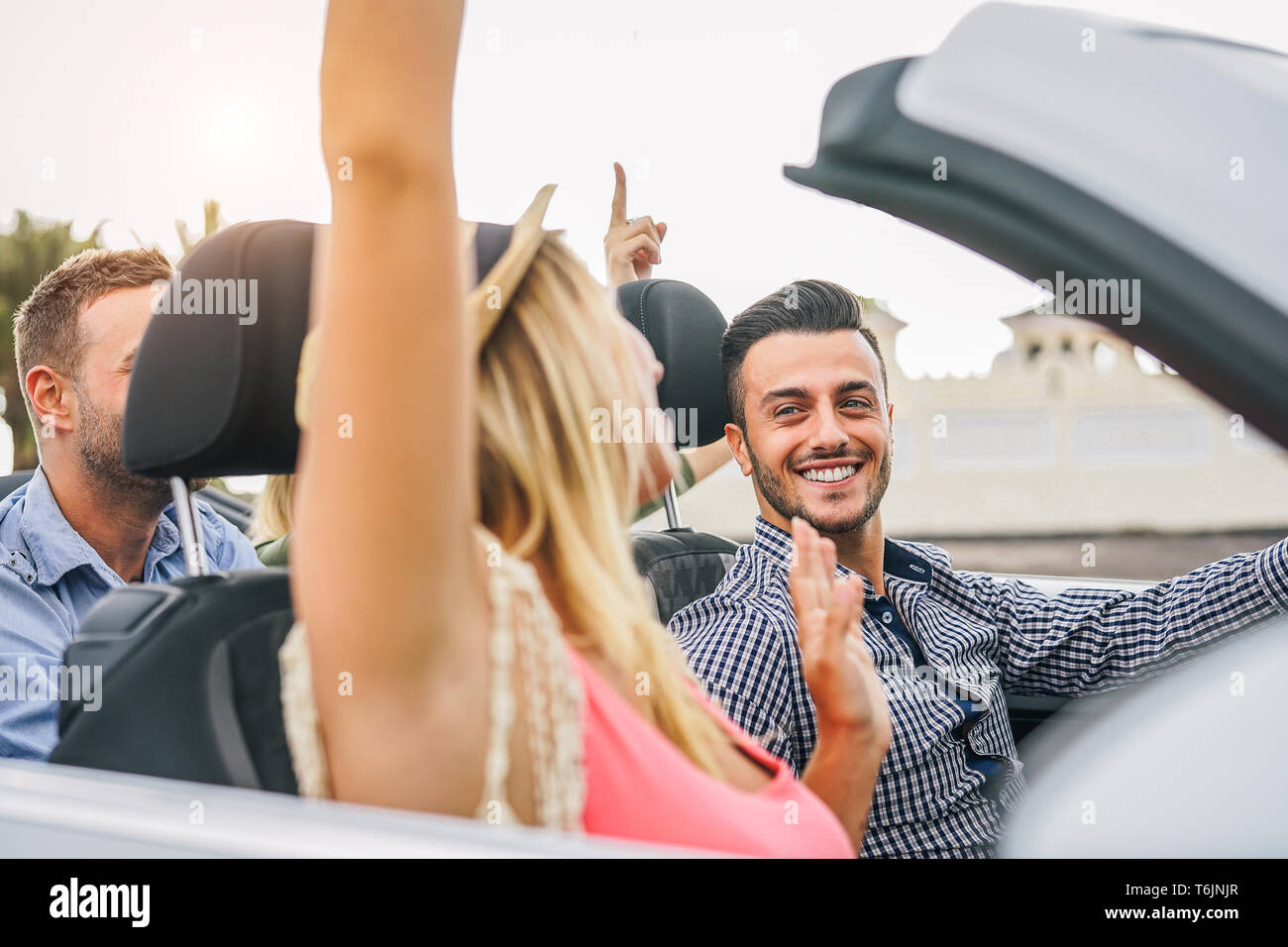 Happy amici divertendosi in autovettura convertibile al tramonto in vacanza - il giovane ricco di persone facendo parte e dancing in auto cabriolet durante il viaggio su strada Foto Stock