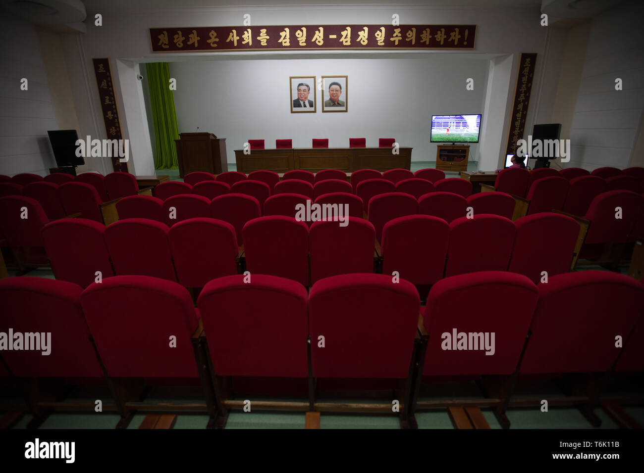 Ritratti di Kim Il Sung e Kim Jong Il adornano la parete al di sopra di una lecture Theatre di Pyongyang. Foto Stock
