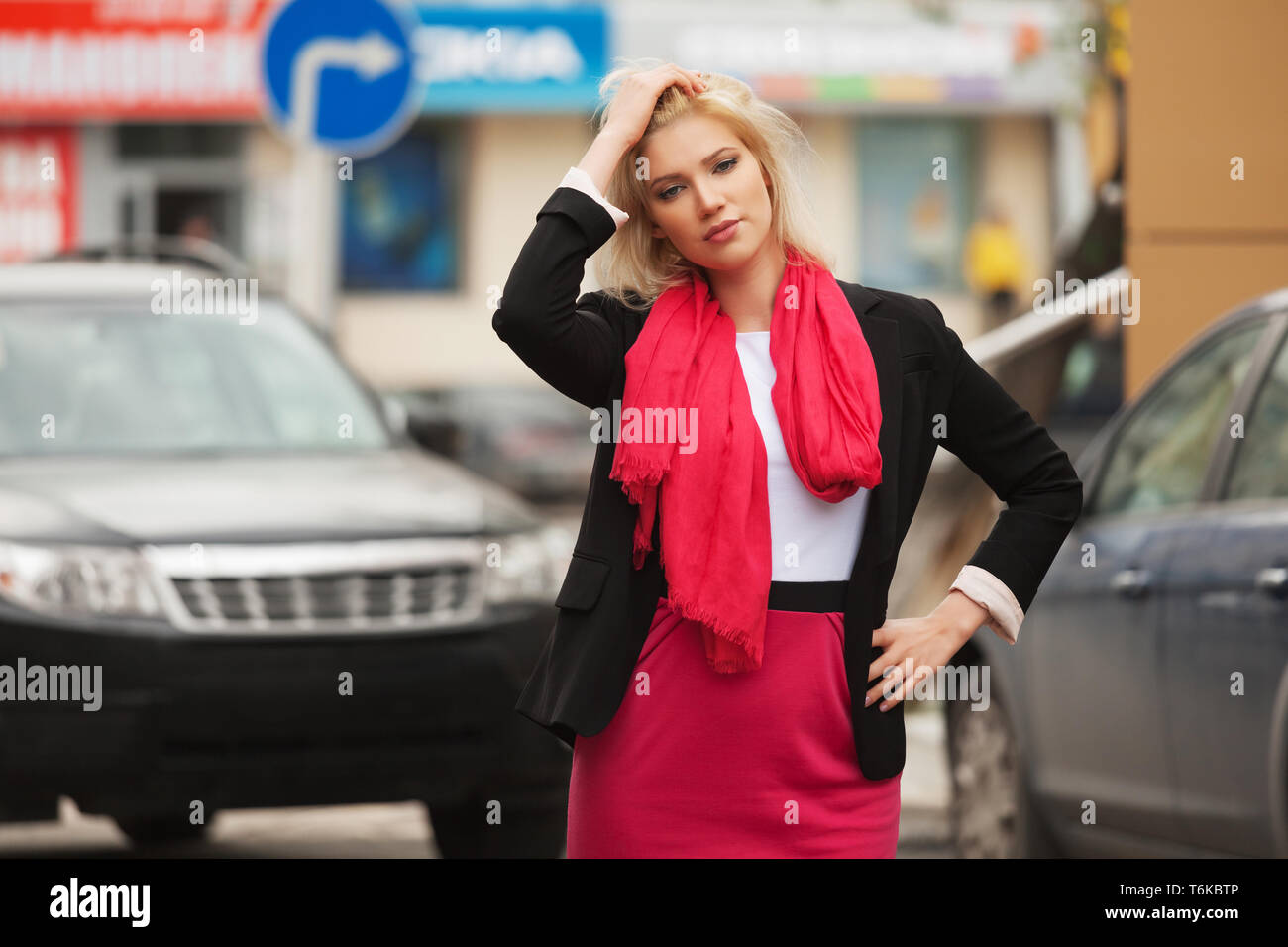 Moda giovane donna di affari a piedi nella città strada elegante modello femminile indossando abito nero giacca e sciarpa rossa all'aperto Foto Stock