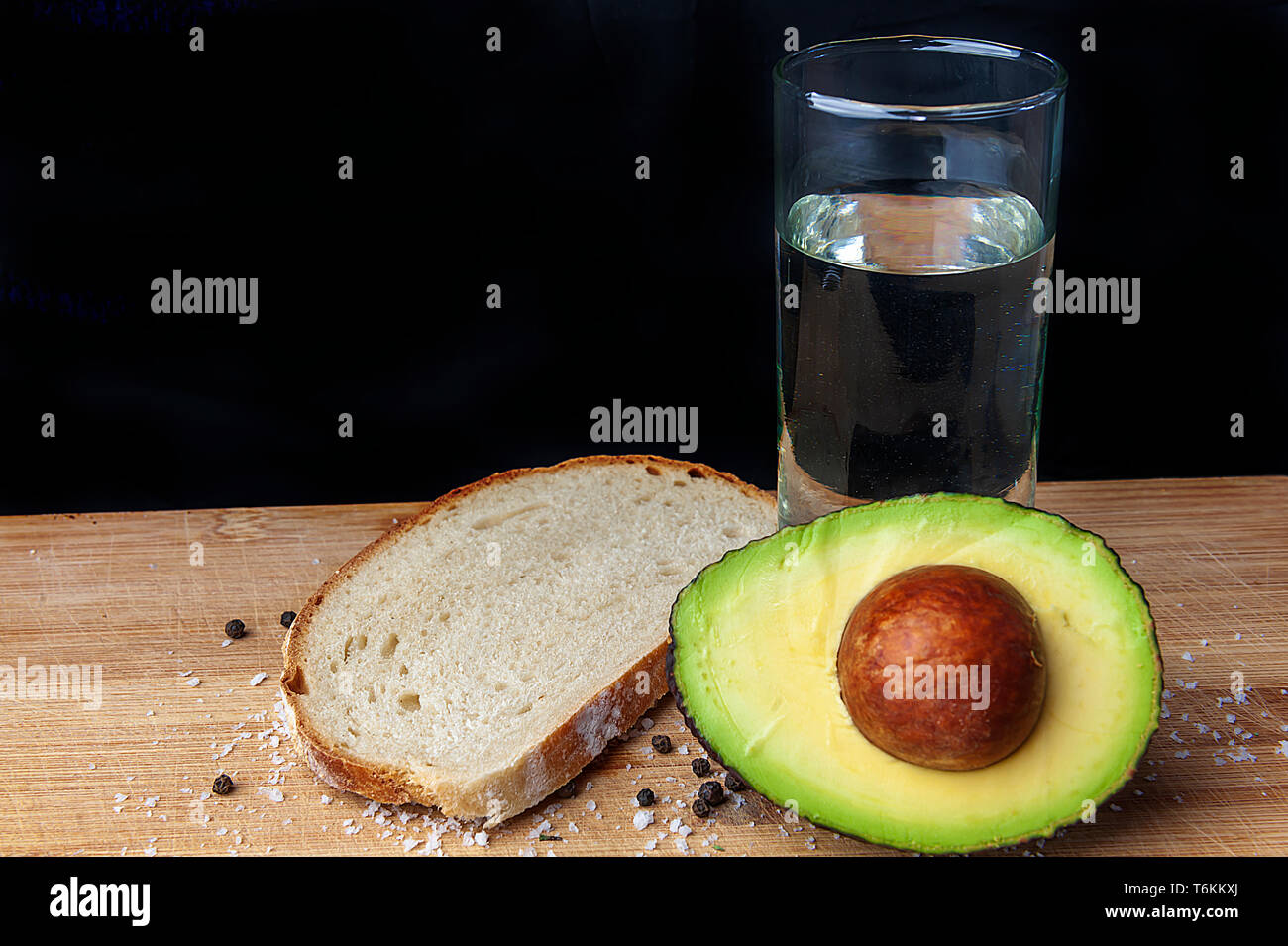 Acqua, avokado ,il pane, il sale, il pepe - studio shot su sfondo nero Foto Stock