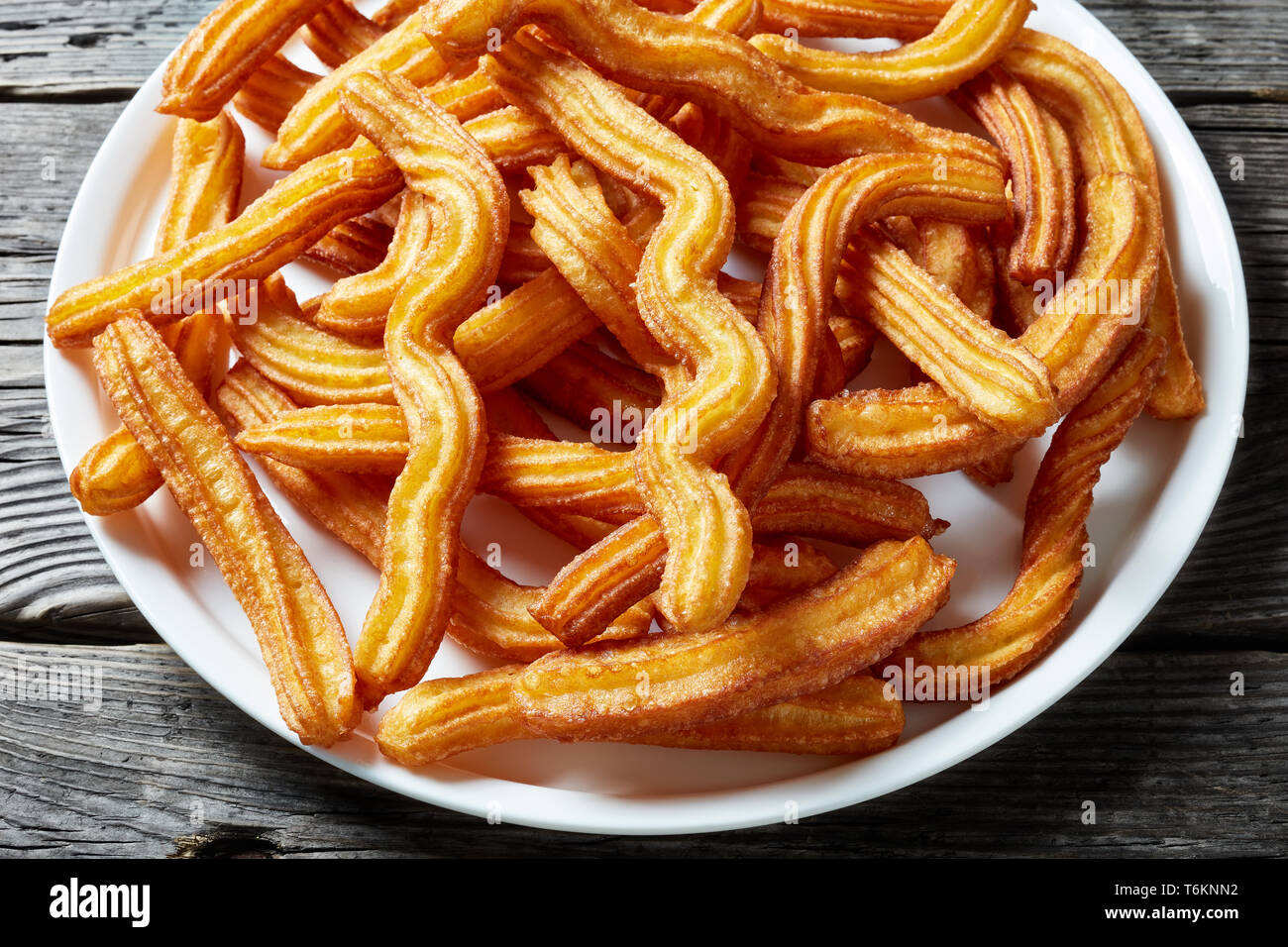 Churros - Tradizionale spagnolo dessert su un piatto bianco su un vecchio grigio a tavola in legno rustico, vista da sopra, close-up Foto Stock