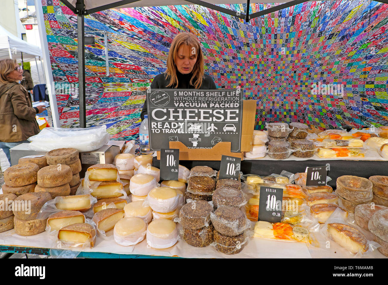 Donna vendita di vari locali portoghesi formaggio formaggi rotondo sul cibo stallo a LX Mercato di fabbrica in Lisbona Lisboa Portogallo KATHY DEWITT Foto Stock