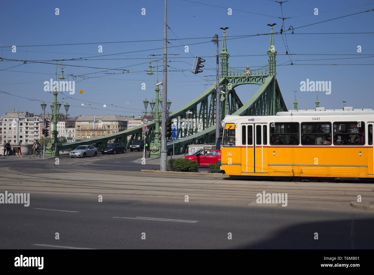 Tram giallo passando dal davanti del Ponte della Libertà a Budapest, Ungheria. Foto Stock