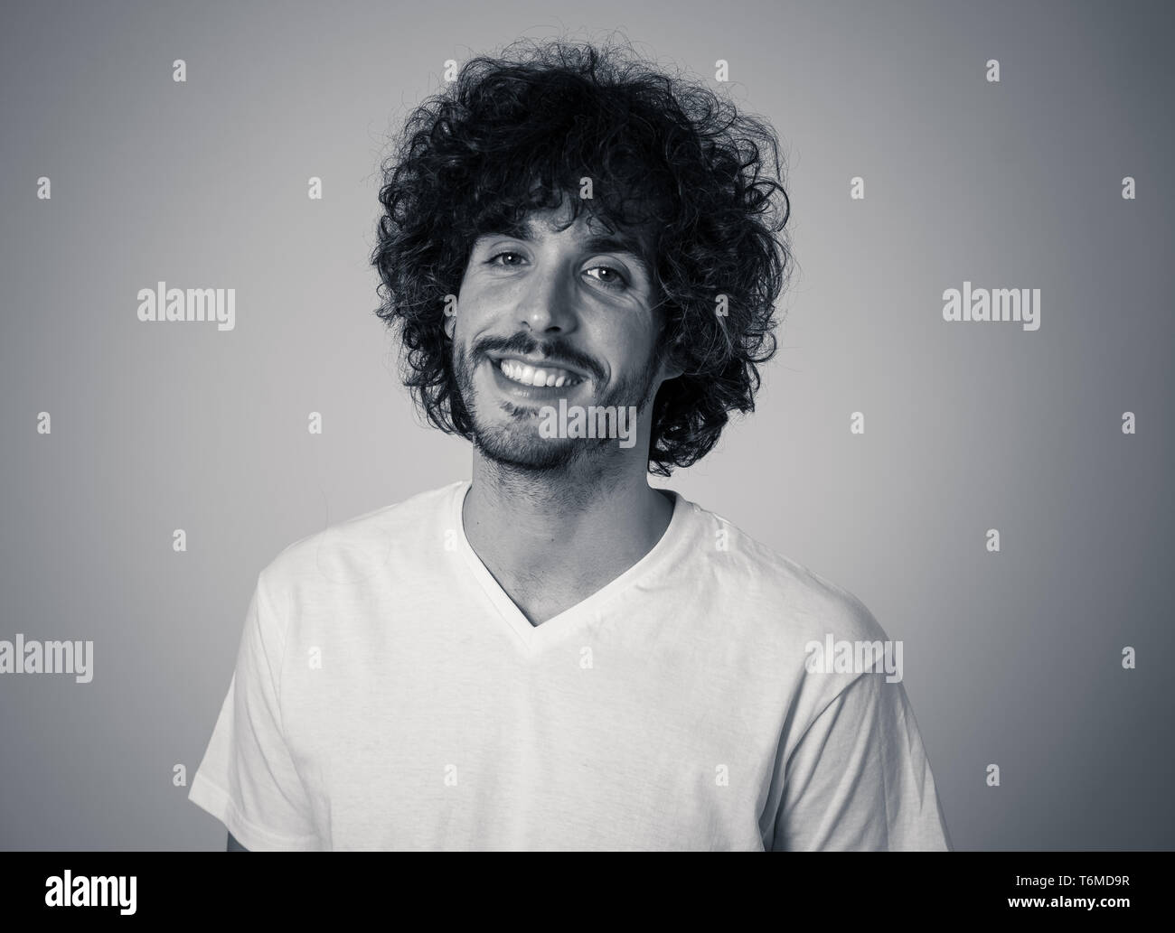 Ritratto di giovane attraente modello con faccia felice, sorriso bellissimo e divertente lo stile dei capelli. Bello millenaria l uomo nella sua 20s. Studio shot. In Persone, Foto Stock