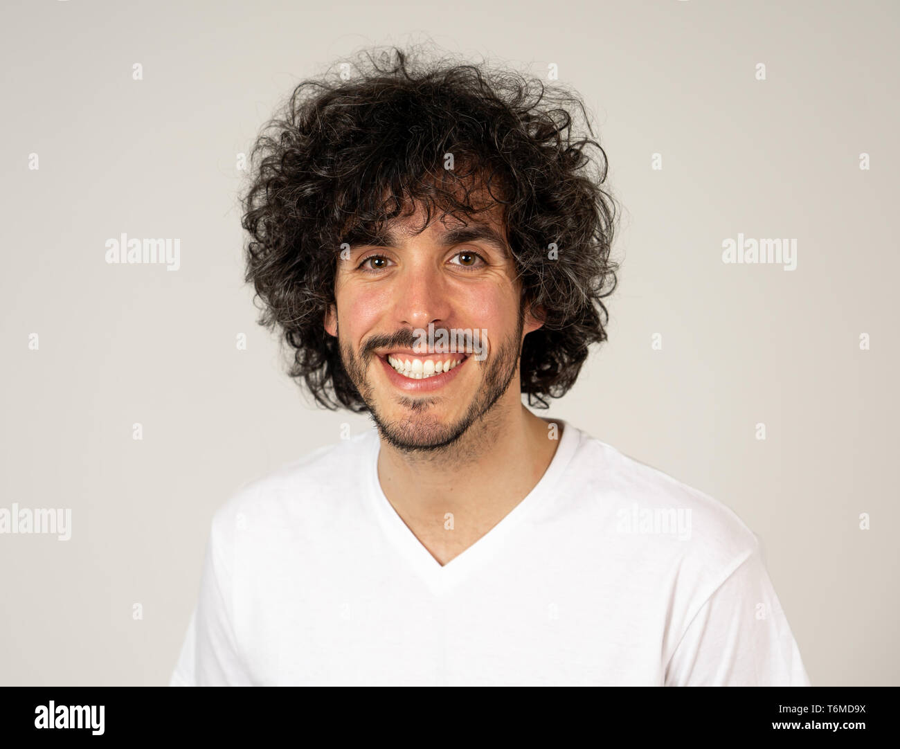Ritratto di giovane attraente modello con faccia felice, sorriso bellissimo e divertente lo stile dei capelli. Bello millenaria l uomo nella sua 20s. Studio shot. In Persone, Foto Stock