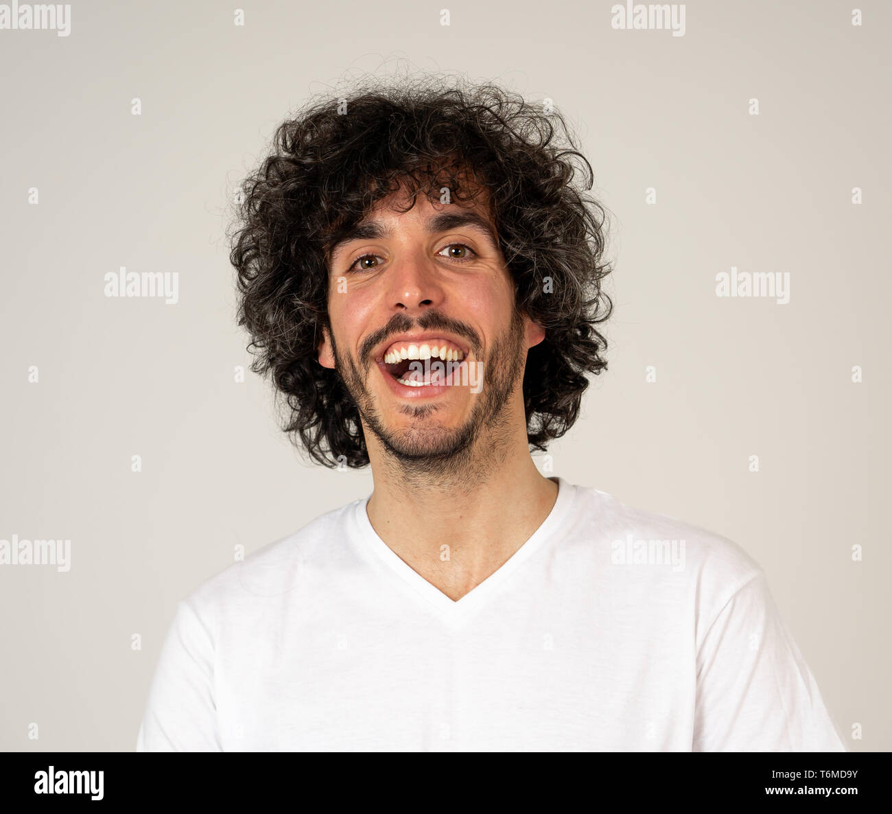 Ritratto di giovane attraente modello con faccia felice, sorriso bellissimo e divertente lo stile dei capelli. Bello millenaria l uomo nella sua 20s. Studio shot. In Persone, Foto Stock