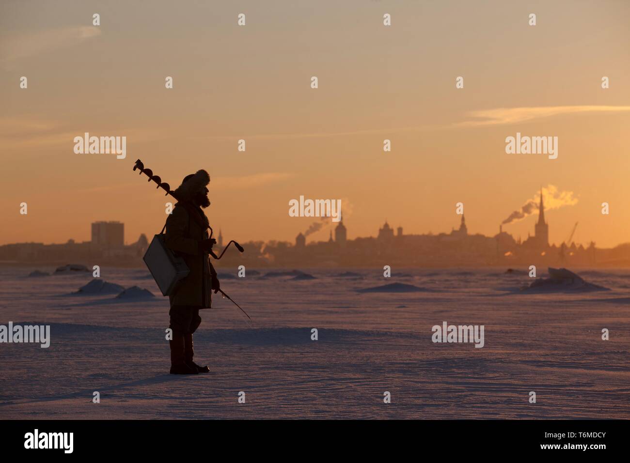 L'uomo la pesca sul ghiaccio contro la silhouette della Città Vecchia di Tallinn Foto Stock