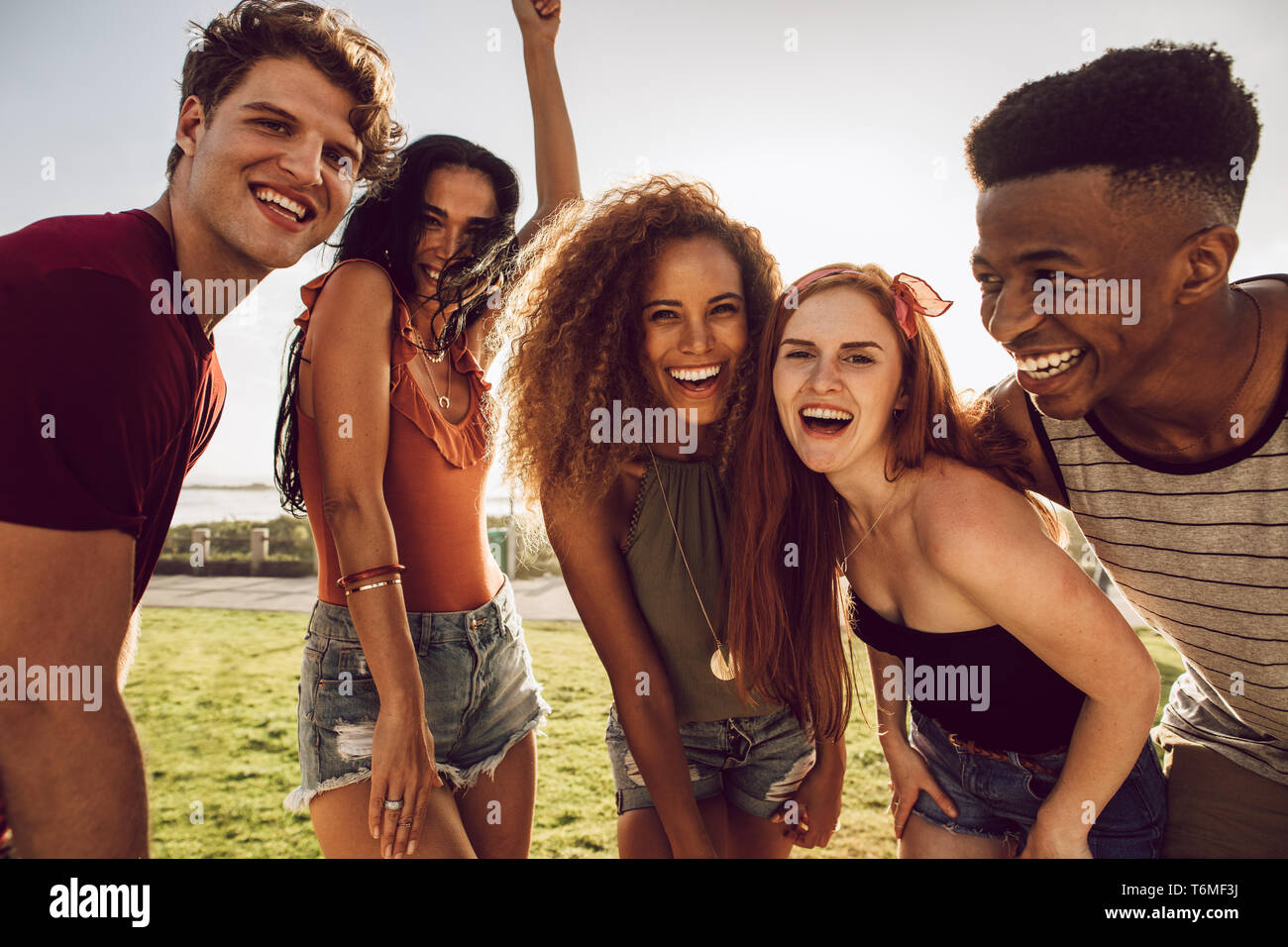 Gruppo di multi-etnico amici balli all'aperto e ridere. Amici avente un grande tempo sulle loro vacanze estive. Foto Stock
