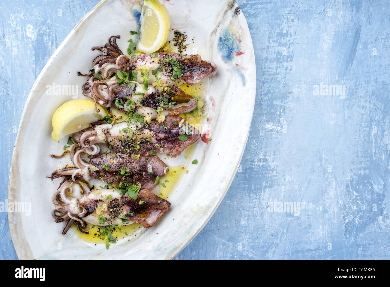 Barbecue tradizionale greco di calamari con erbe e limone come vista dall'alto su una piastra Foto Stock
