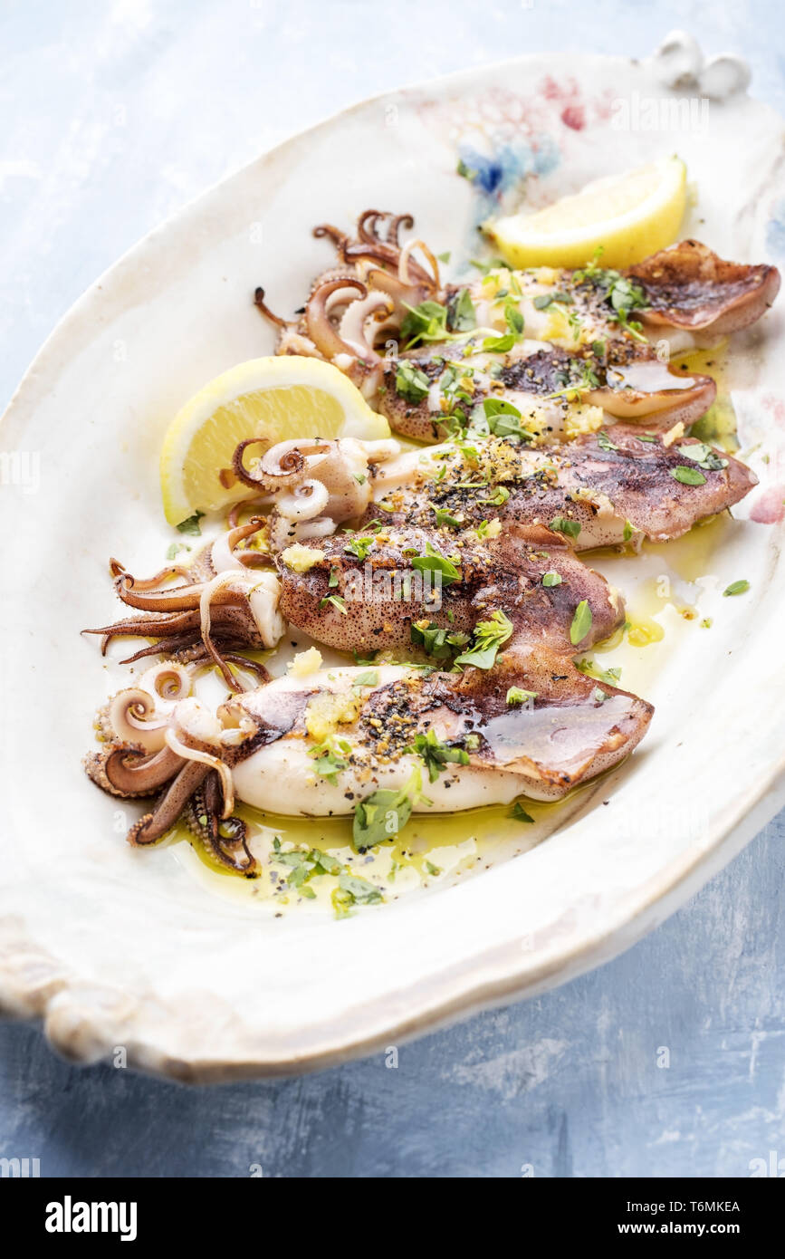 Barbecue tradizionale greco di calamari con erbe e limone come vista dall'alto su una piastra Foto Stock