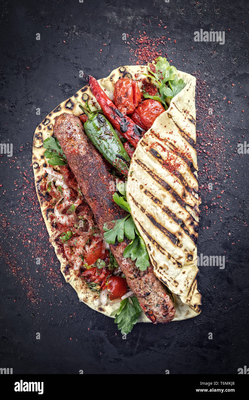 Tradizionali di Adana Kebap con pomodoro e insalata su un flatbread con spazio di copia Foto Stock