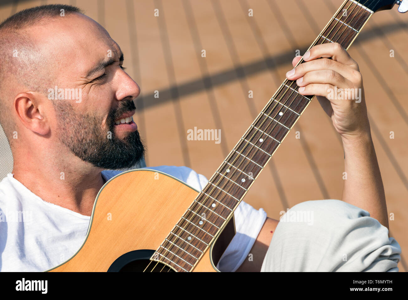 Ritratto di un uomo spagnolo con la barba e breve buzz capelli, suonando una chitarra acustica all'esterno. Foto Stock