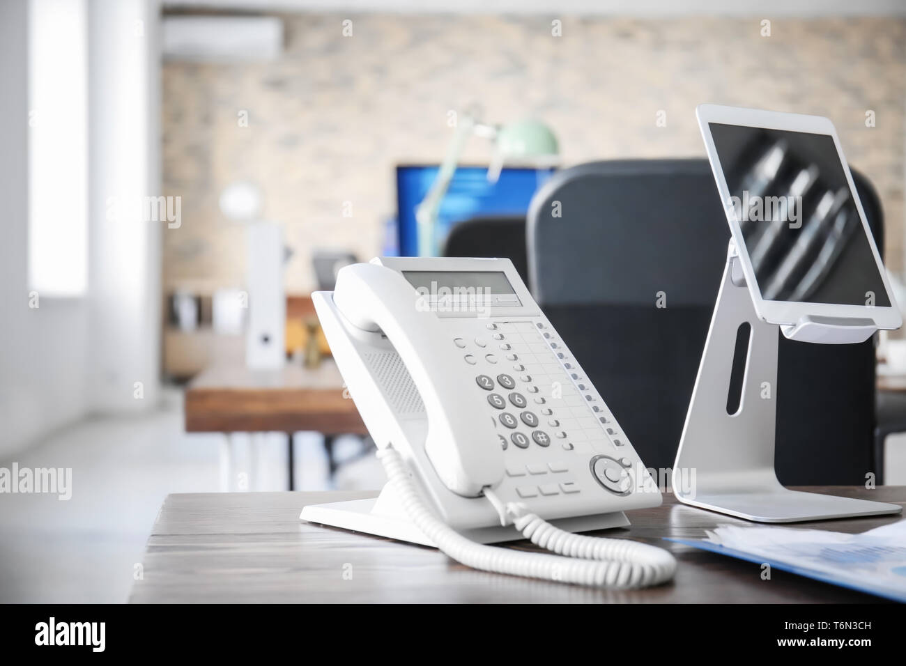 Il luogo di lavoro con telefono fisso e computer tablet sul tavolo in ufficio moderno Foto Stock