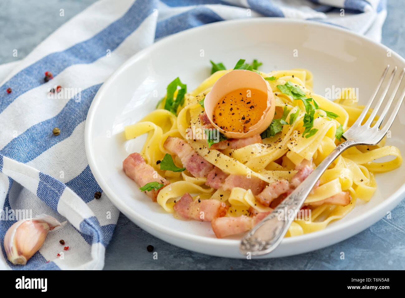 La pasta alla carbonara con tuorlo d'uovo e la forcella nella piastra. Foto Stock