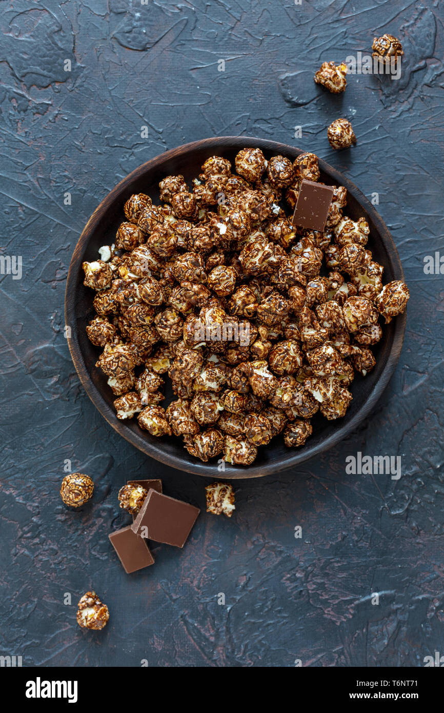 Caramel popcorn di cioccolato su un tagliere di legno. Foto Stock