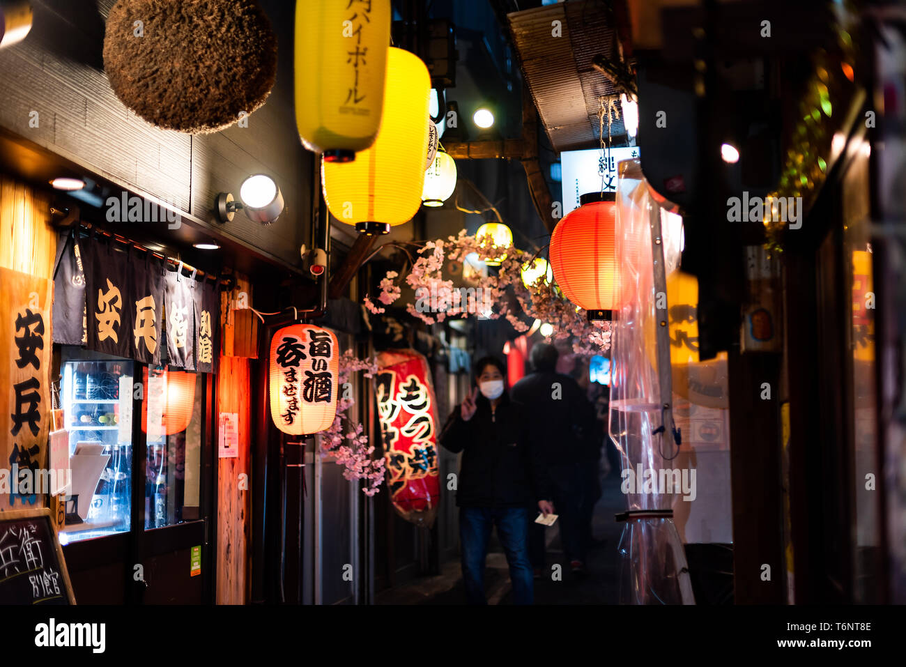 Tokyo, Giappone - Aprile 3, 2019: Memory lane alley con decorazioni e carta gialla lampade lanterne e persone nella zona di Shinjuku della città di notte Foto Stock