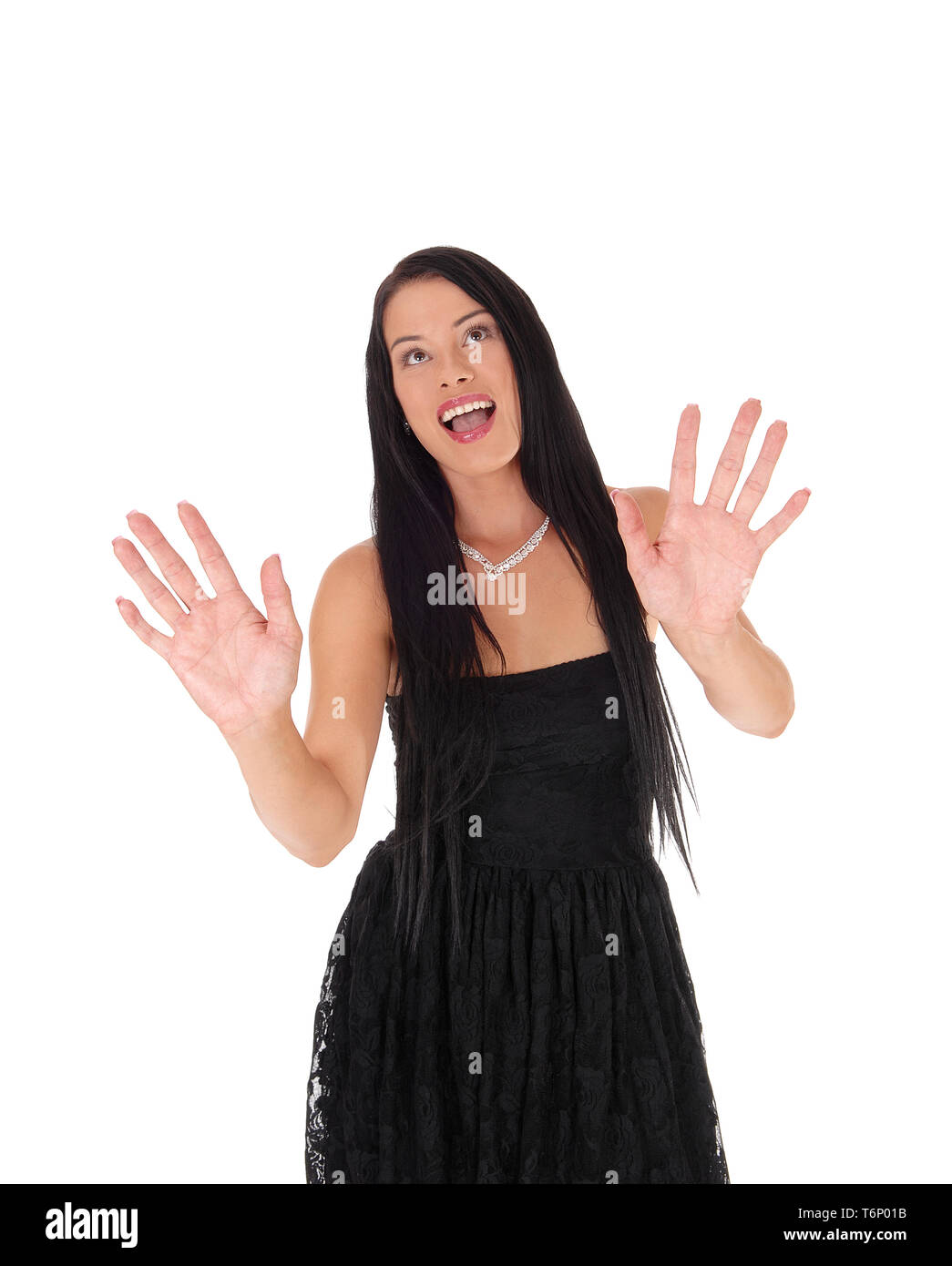 Spaventata donna in piedi in abito nero mani sollevate Foto Stock