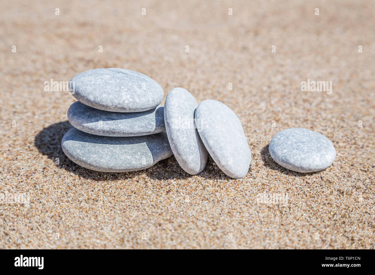 Pila di pietre ghiaia sbilanciato su di una spiaggia di sabbia con spazio di copia Foto Stock