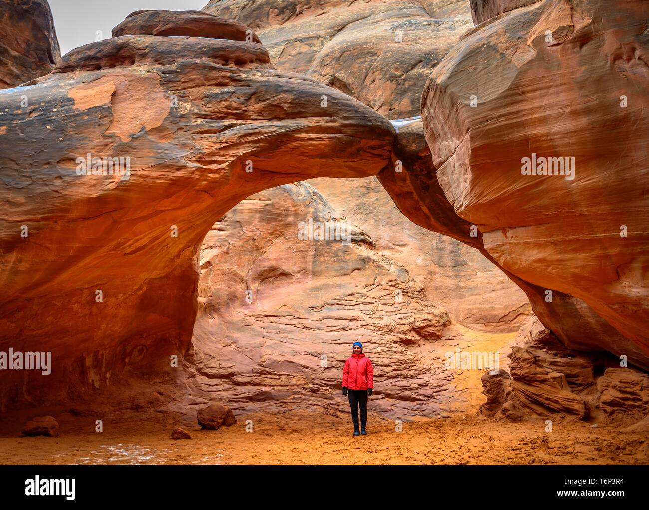 Donna in piedi sotto la roccia arch, Dune di sabbia Arch, Arches National Park, vicino a Moab, Utah, Stati Uniti d'America Foto Stock