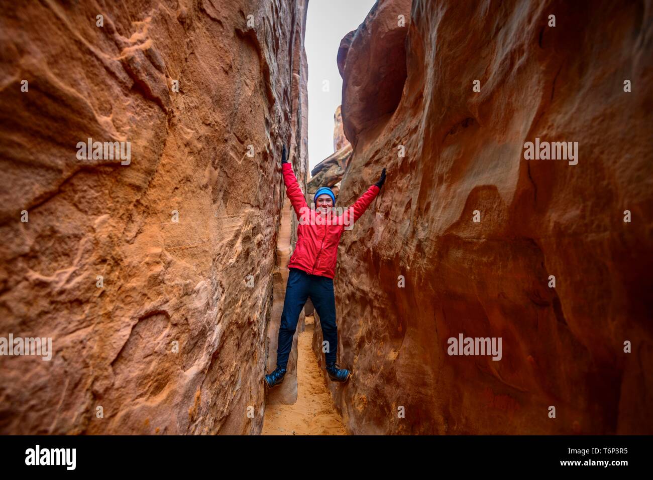 Giovane donna in piedi di spazio tra le rocce, Dune di sabbia Arch, Arches National Park, vicino a Moab, Utah, Stati Uniti d'America Foto Stock